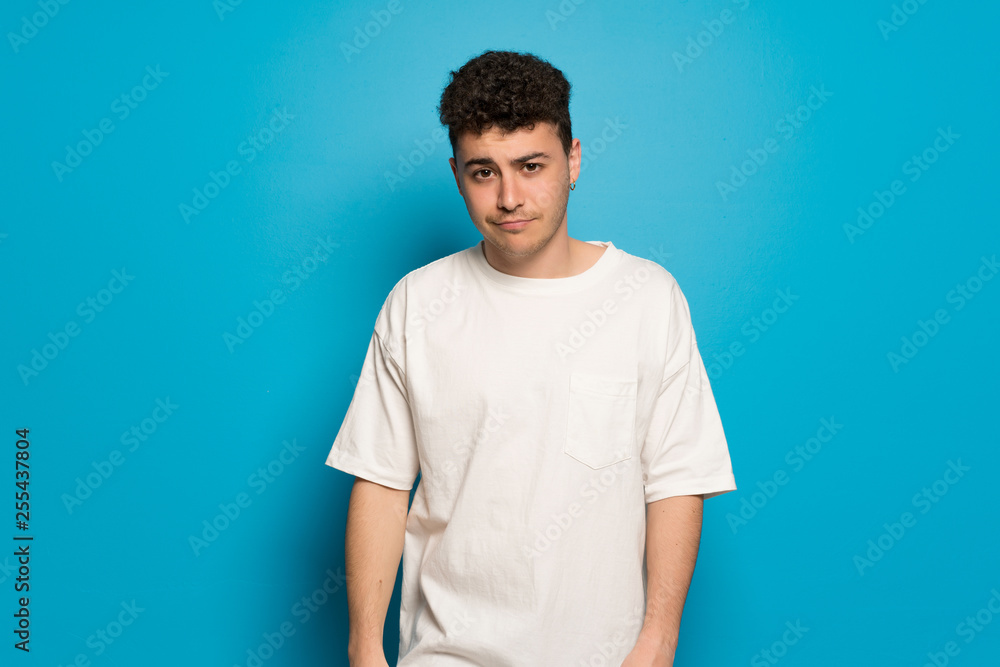 Young man over blue background with sad and depressed expression Young man over blue background with sad and depressed expression
