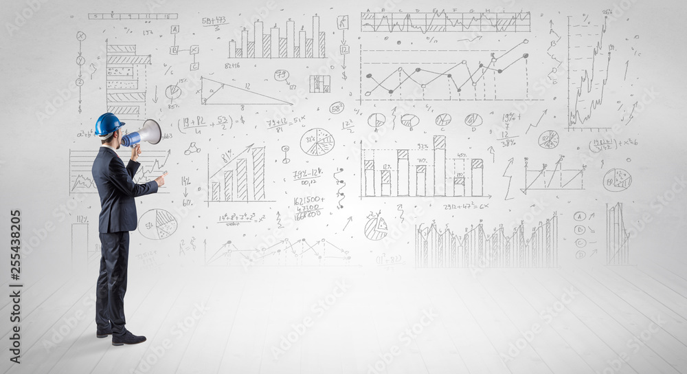 Engineer with construction helmet holding a plan and standing with graphs, charts and reports on the background Engineer with construction helmet holding a plan and standing with graphs, charts and reports on the background