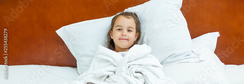 cute smiling little girl woke up in white bed photo