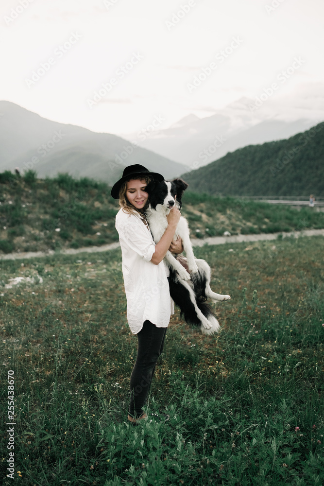 pretty girl and black and white dog border collie on her hands. mountain in field