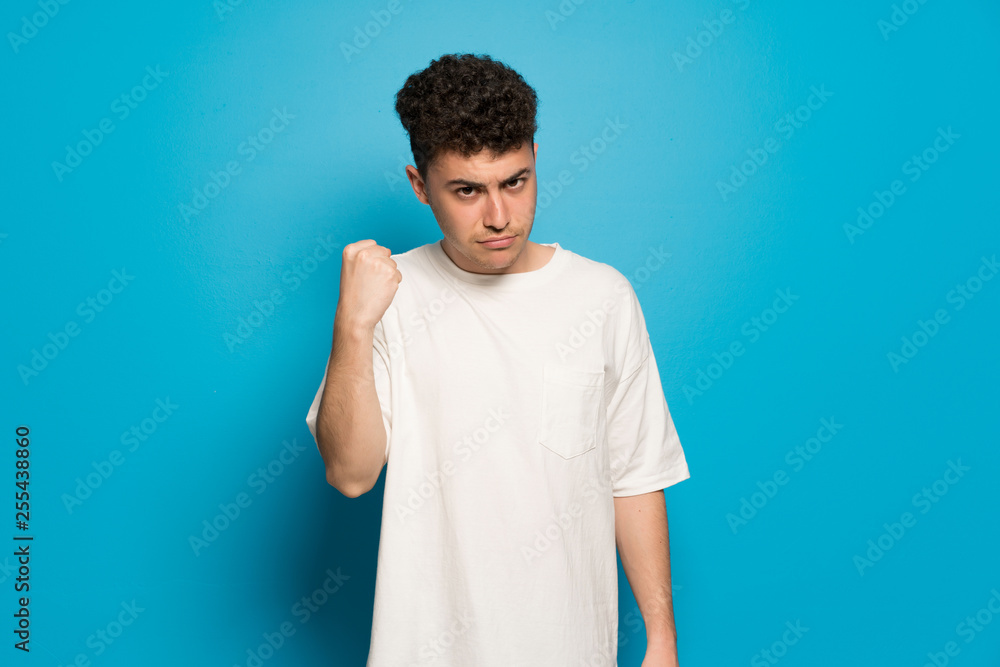Young man over blue background with angry gesture Young man over blue background with angry gesture