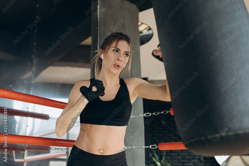 Female Punching a Boxing bag With Boxing Gloves at the gym