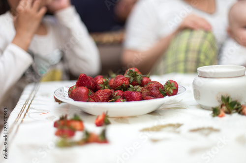 Sweet fresh strawberries on a plate on the table for  hands take and keep ripe red strawberries  a bunch of fresh strawberries in a ceramic bowl on a white table background