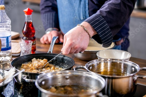 Chef mixes pieces of fish, frying them in a pan. Master class in the kitchen. The process of cooking. Step by step. Tutorial. Close-up