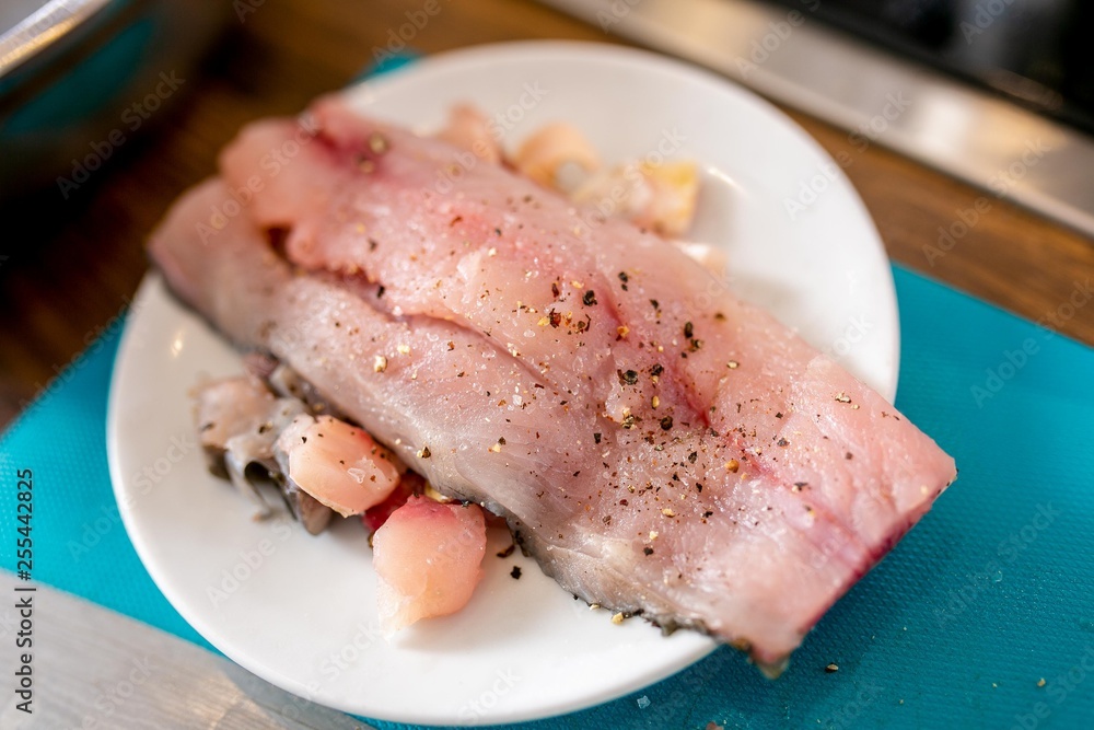 Piece of raw fish with spices on a plate. Master class in the kitchen. The process of cooking. Step by step. Tutorial. Close-up Piece of raw fish with spices on a plate. Master class in the kitchen. The process of cooking. Step by step. Tutorial. Close-up