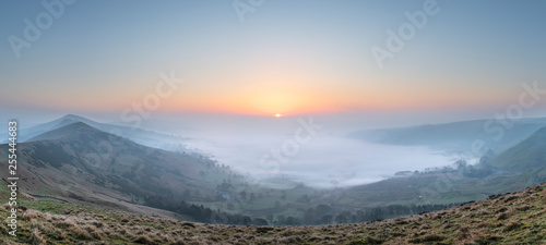 Stunning Winter sunrise landscape image of The Great Ridge in the Peak Distrit in England with a cloud inversion and mist in the Hope Valley with a lovely orange glow