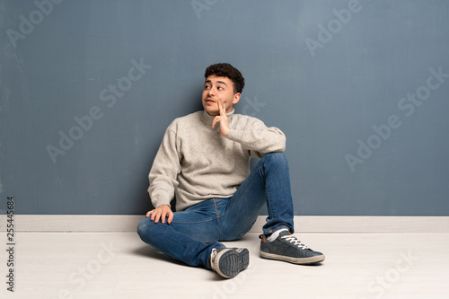 Young man sitting on the floor thinking an idea while looking up