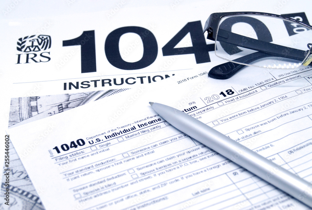 Income tax form with instruction, glasses and pen