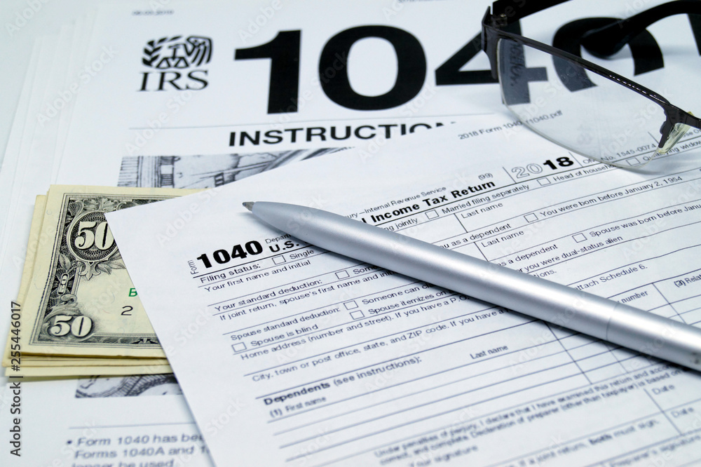 Income tax form with instruction, glasses and pen.