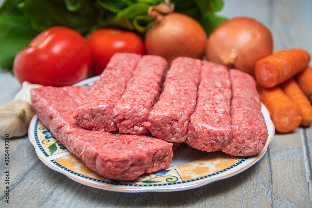 Minced meat for Kebab ready for barbeque. Traditional middle eastern and mediterranean eat. With fresh organic vegetable in the background. Minced meat for Kebab ready for barbeque. Traditional middle eastern and mediterranean eat. With fresh organic vegetable in the background.