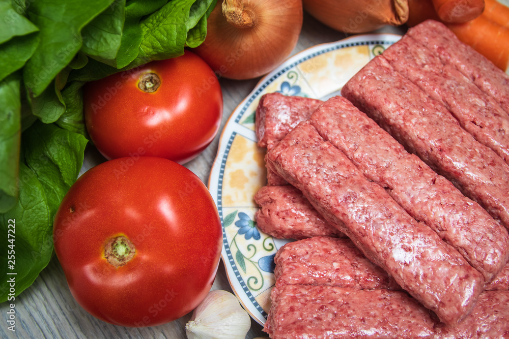 Minced meat for Kebab ready for barbeque. Traditional middle eastern and mediterranean eat. With fresh organic vegetable in the background.
