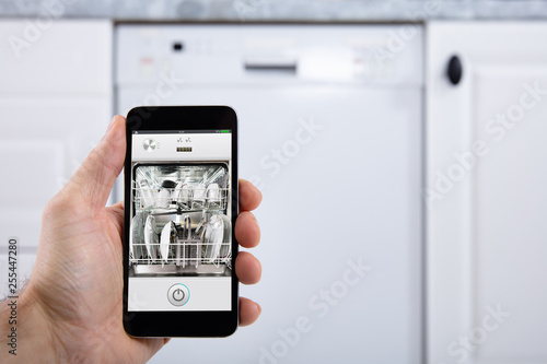 Person Operating Dishwasher With Smartphone