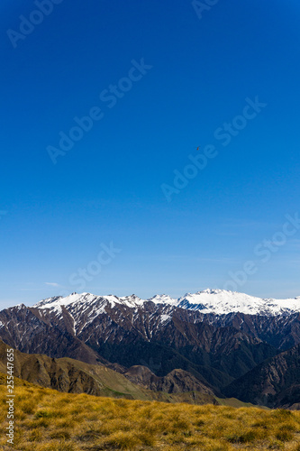 idillic landscape with mountain range, brown hills during sunny day, perfect hiking area, small helicopter on the sky