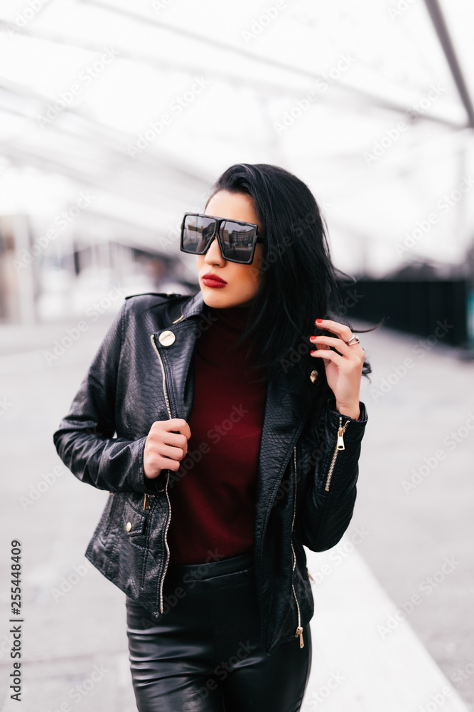 Fototapeta premium Fashion portrait woman in sunglasses outdoor. Young smiling woman wearing a rock black style having fun in city. Street fashion.
