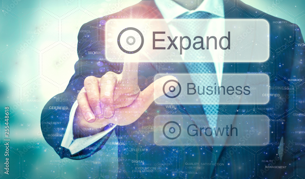 A business man selection a button on a futuristic display with a Expand concept written on it.