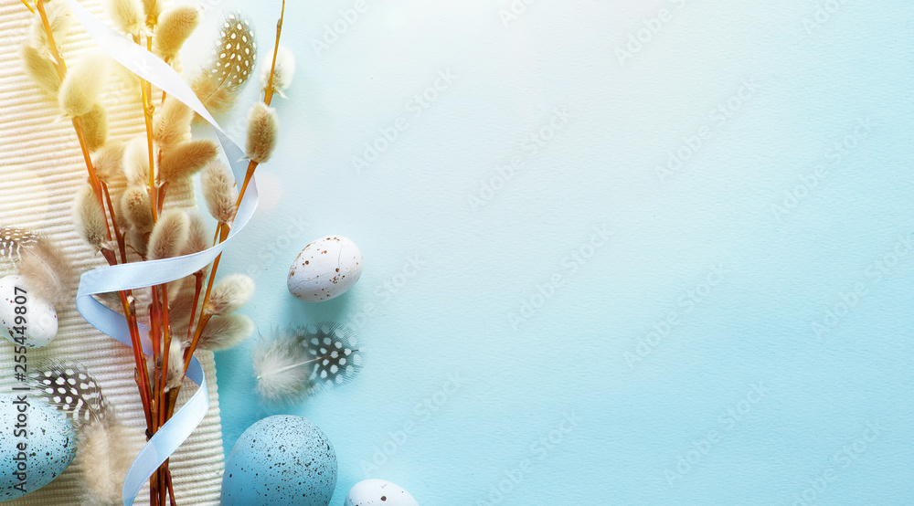 Fototapeta Wielkanocny kartka z pozdrowieniami z kolorowymi Easter jajkami i sprin flowersl na błękita stole. Widok z góry z miejscem na pozdrowienia - Zdjęcie