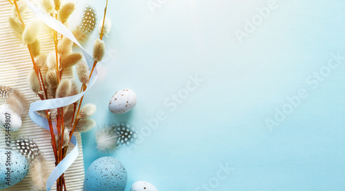Easter greeting card with colorful easter eggs and sprin flowersl on blue table. Top view with space for your greetings - Image