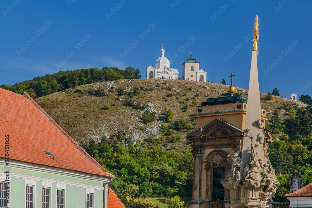 A hill with Way of the Cross in South Moravia, Czech Republic, close to Mikulov town, called Holly Hill with Saint Sebastians Chapel and a bell tower, sunny day, blue sky, golden cross