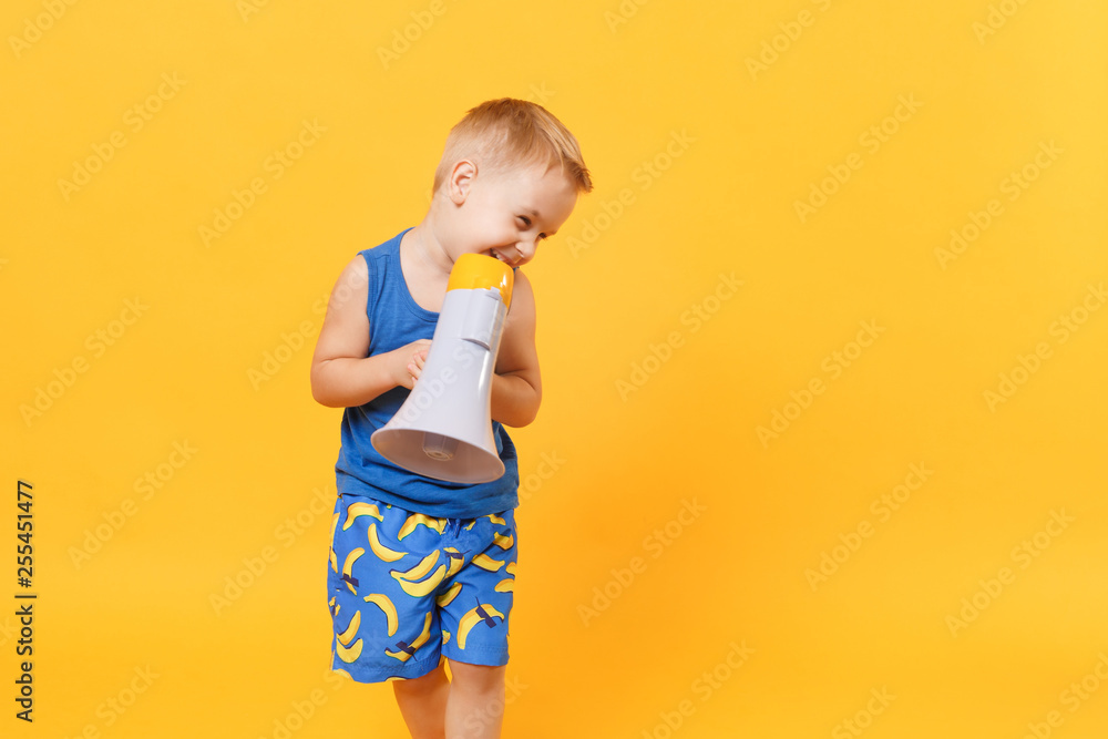 Kid boy 3-4 years old in blue beach summer clothes hold speak in megaphone isolated on bright yellow orange background children studio portrait. People childhood lifestyle concept Mock up copy space. Kid boy 3-4 years old in blue beach summer clothes hold speak in megaphone isolated on bright yellow orange background children studio portrait. People childhood lifestyle concept Mock up copy space.