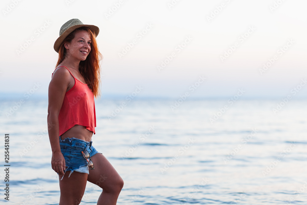 Portrait of a young woman by the sea enjoying sunset