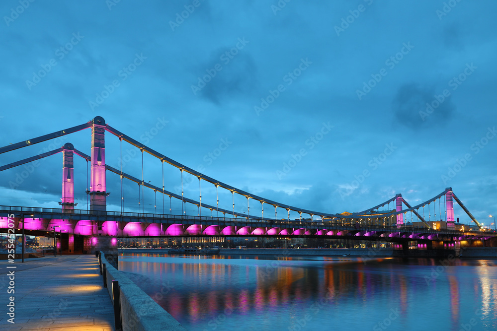 Krymsky Bridge or Crimean Bridge  across the Moskva river in Moscow in the rays of setting sun in the evening blue hour with illumination