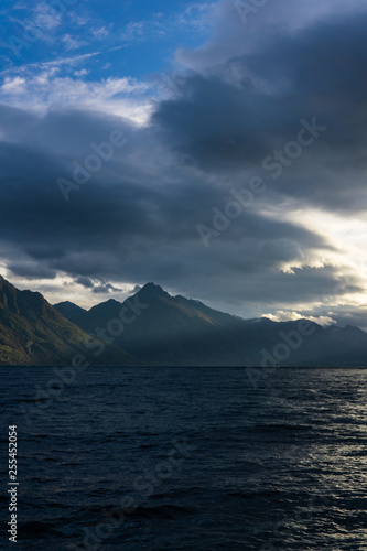 peaceful landscape during sunset with dramatic sky above the lake and mountain range