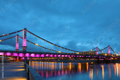 Krymsky Bridge or Crimean Bridge across the Moskva river in Moscow in the rays of setting sun in the evening blue hour with illumination