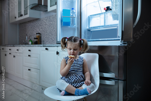 Girl Eating Cupcake Sitting In Front Of Open Refrigerator