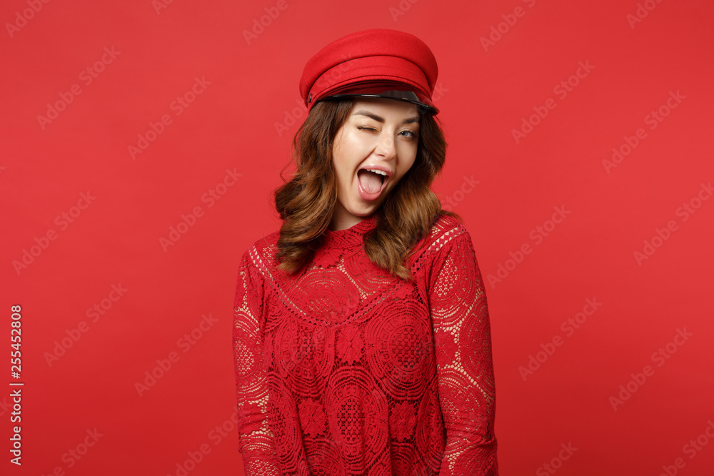 Portrait of cheerful blinking young woman in lace dress, cap looking camera keeping mouth open isolated on red wall background in studio. People sincere emotions lifestyle concept. Mock up copy space. Portrait of cheerful blinking young woman in lace dress, cap looking camera keeping mouth open isolated on red wall background in studio. People sincere emotions lifestyle concept. Mock up copy space.