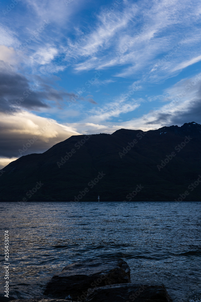 calm landscape during sunset with dramatic sky over lake and dark mountain