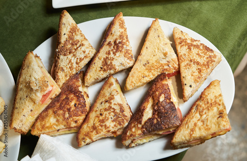 Various triangle toasts sandwiches on a white plate, close-up