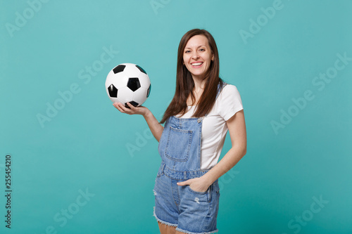 Smiling young woman football fan support favorite team holding soccer ball isolated on blue turquoise background in studio. People emotions, sport family leisure lifestyle concept. Mock up copy space. © ViDi Studio