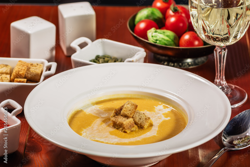 Spicy Pumpkin or lentil soup with cream an croutons in white plate on wooden background Spicy Pumpkin or lentil soup with cream an croutons in white plate on wooden background