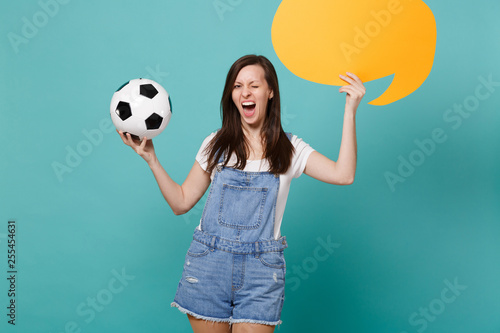 Blinking funny girl football fan cheer up support team with soccer ball empty blank yellow Say cloud speech bubble isolated on blue turquoise background. People emotions, sport family leisure concept. photo