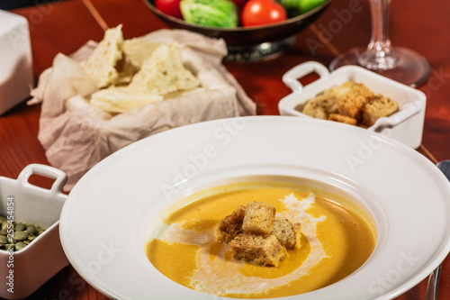 Pumpkin cream soup with croutons, baked chickpeas, sesame, parsley on a brown wooden background. Baked chickpeas with spices. Useful dietary snacks. Served with white wine and cheese