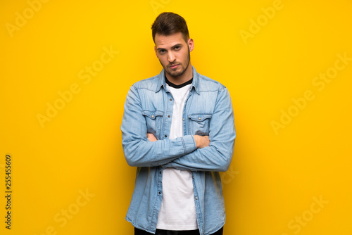 Handsome man over yellow wall with sad and depressed expression