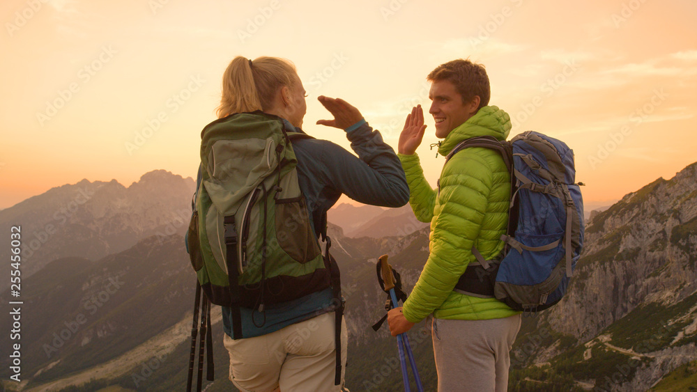 CLOSE UP: Happy woman and her boyfriend high five after reaching the mountaintop
