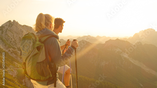 CLOSE UP Happy woman and boyfriend watch the golden sunset illuminating the Alps