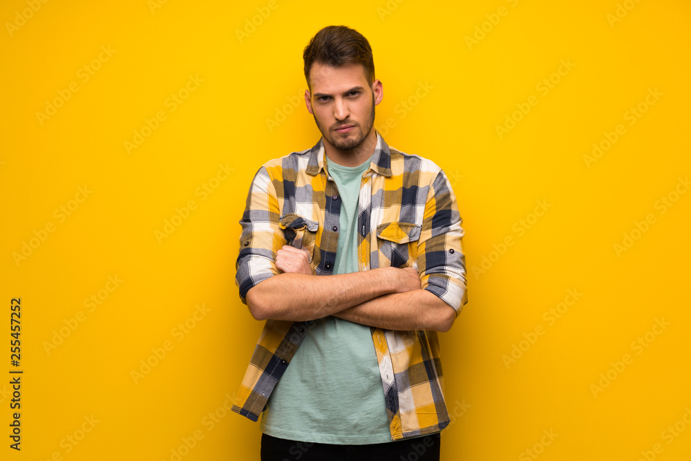 Handsome man over yellow wall frustrated by a bad situation Handsome man over yellow wall frustrated by a bad situation