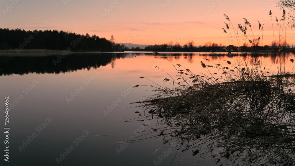 red sunset over the water of a village lake