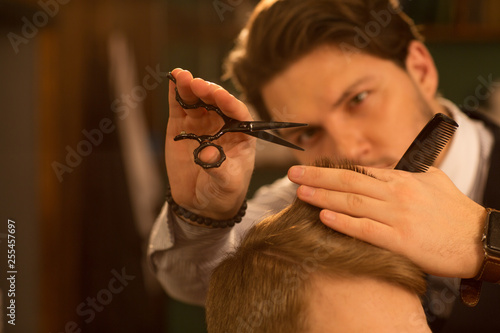 Selective focus on the hands of a professional barber using scissors and a comb cutting hair of his client copyspace service hairdresser barbershop stylist hairstyling profession barbering job traditi