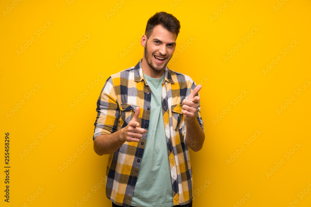 Handsome man over yellow wall pointing to the front and smiling Handsome man over yellow wall pointing to the front and smiling
