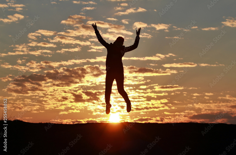 Silhouette of a happy girl jumping into the sky against the backdrop of an incredible sunset, sky and clouds Silhouette of a happy girl jumping into the sky against the backdrop of an incredible sunset, sky and clouds