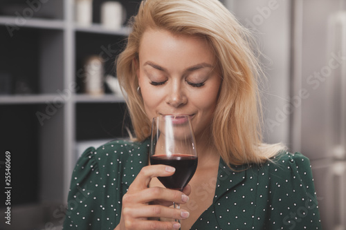 Tablou pe pânză Gorgeous young woman smiling with her eyes closed, smelling delicious red wine in her glass