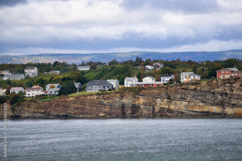 Residential homes on a rocky coast during a cloudy day. Taken in North Sydney, Nova Scotia, Canada.