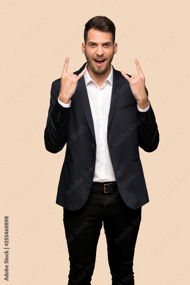 Handsome business man making rock gesture over ocher background Handsome business man making rock gesture over ocher background