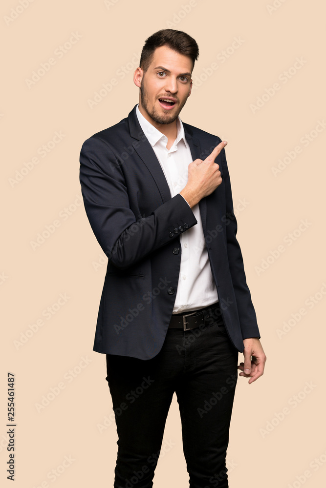 Handsome business man surprised and pointing side over ocher background Handsome business man surprised and pointing side over ocher background