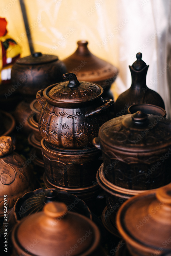 A lot of pottery at the fair. Ceramic national Russian dishes made. Burnt black ceramics. Burnt clay pots and plates, dishes A lot of pottery at the fair. Ceramic national Russian dishes made. Burnt black ceramics. Burnt clay pots and plates, dishes