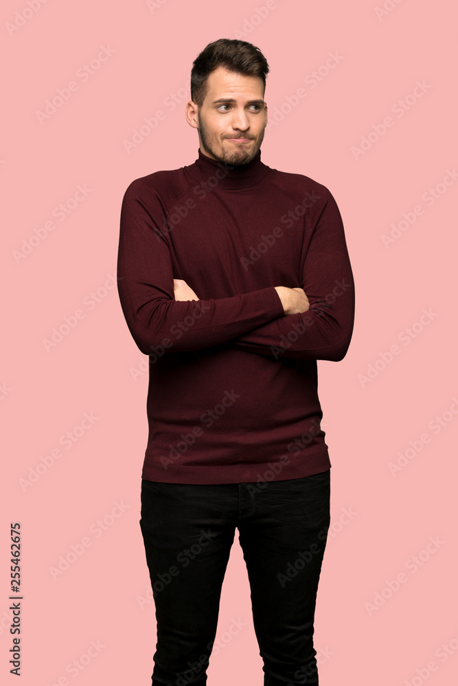 Man with turtleneck sweater making doubts gesture while lifting the shoulders over pink background Man with turtleneck sweater making doubts gesture while lifting the shoulders over pink background