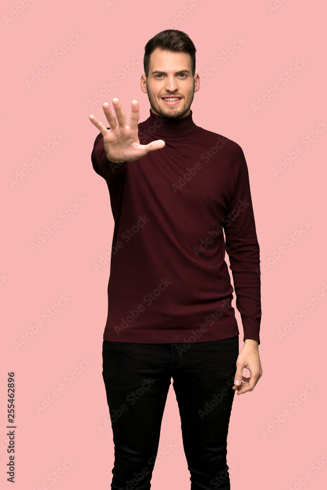 Man with turtleneck sweater counting five with fingers over pink background Man with turtleneck sweater counting five with fingers over pink background